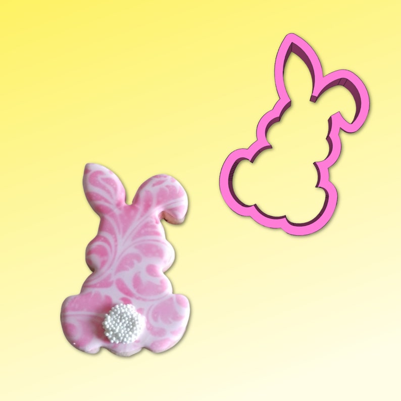 May include: Pink bunny cookie cutter and a pink bunny cookie decorated with white marbling and white sprinkles.