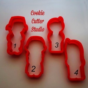 May include: Four red plastic cookie cutters shaped like people. The cutters are numbered 1 through 4. The text "Cookie Cutter Studio" is visible above the cutters.