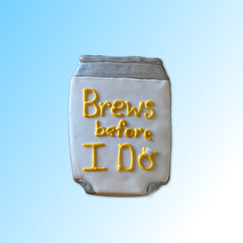 May include: A white iced cookie shaped like a can of beer with the words "Brews before I Do" in yellow icing.