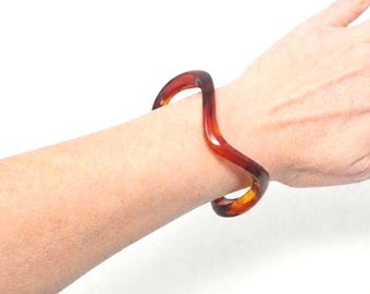 Pulsera rígida vintage de baquelita con efecto mármol color carey ámbar y forma ondulada orgánica.