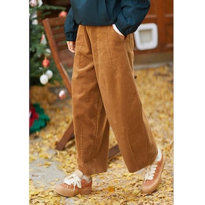 May include: Brown corduroy pants with a wide leg and a relaxed fit. The pants have a high waist and are made of a soft, comfortable fabric.