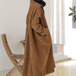 May include: A long brown corduroy coat with a button-up front and a drawstring waist.