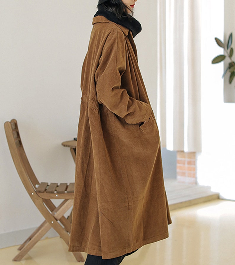 May include: A long brown corduroy coat with a button-up front and a drawstring waist.
