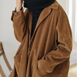 May include: A brown corduroy long-sleeved jacket with a button-up front and two pockets. The jacket has a relaxed fit and a collar.