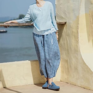 May include: A light blue linen blouse with a white lace trim and a blue and white checkered linen pants.