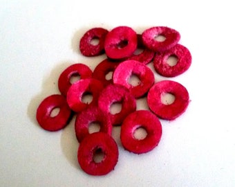 May include: A group of 12 pink leather donut-shaped rings. The rings are all the same size and have a smooth, polished finish.