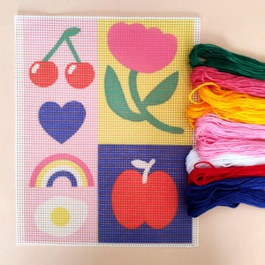 Peut inclure: Une toile de point de croix color&eacute;e avec un motif en grille repr&eacute;sentant une cerise, un c&oelig;ur, un arc-en-ciel, une fleur, une pomme et une marguerite. Accompagn&eacute;e d'un ensemble de fils &agrave; broder multicolores : vert, rose, jaune, blanc, rouge et bleu.