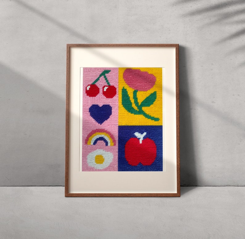 Peut inclure: Une &oelig;uvre d'art encadr&eacute;e avec un motif cousu en quatre carr&eacute;s. Les carr&eacute;s contiennent des images de cerises, d'un c&oelig;ur, d'un arc-en-ciel et d'une pomme. Les couleurs de fond sont rose, jaune et bleu. Le cadre est de couleur marron chaud.