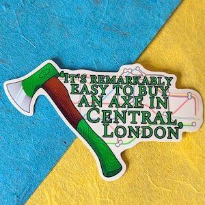 Pode incluir: Adesivo com um machado de desenho animado com cabo verde e lâmina prateada. O texto diz: "É notavelmente fácil comprar um machado em Central London". Fundo azul e amarelo.