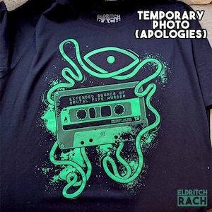 May include: Black t-shirt with a green graphic of a cassette tape and an eye, with the text "EXTENDED SOUNDS OF BRUTAL PIPE MURDER." The shirt also has the text "TEMPORARY PHOTO (APOLOGIES)" and the brand name "ELDRITCH RACH."