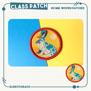 Puede incluir: Un parche tejido de 40 mm que presenta un conejo azul y blanco con un sol rojo, amarillo y blanco detr&aacute;s. El parche est&aacute; sobre un fondo amarillo con un borde azul.