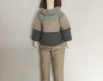 Handmade fabric doll/ person long brown hair in a ponytail. Beige boots, beige and greys jumper, beige trousers with grey spot