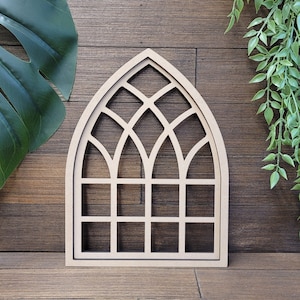 May include: A wooden cutout of an arched window with a stained glass design. The window is made of multiple squares and has a pointed arch at the top.