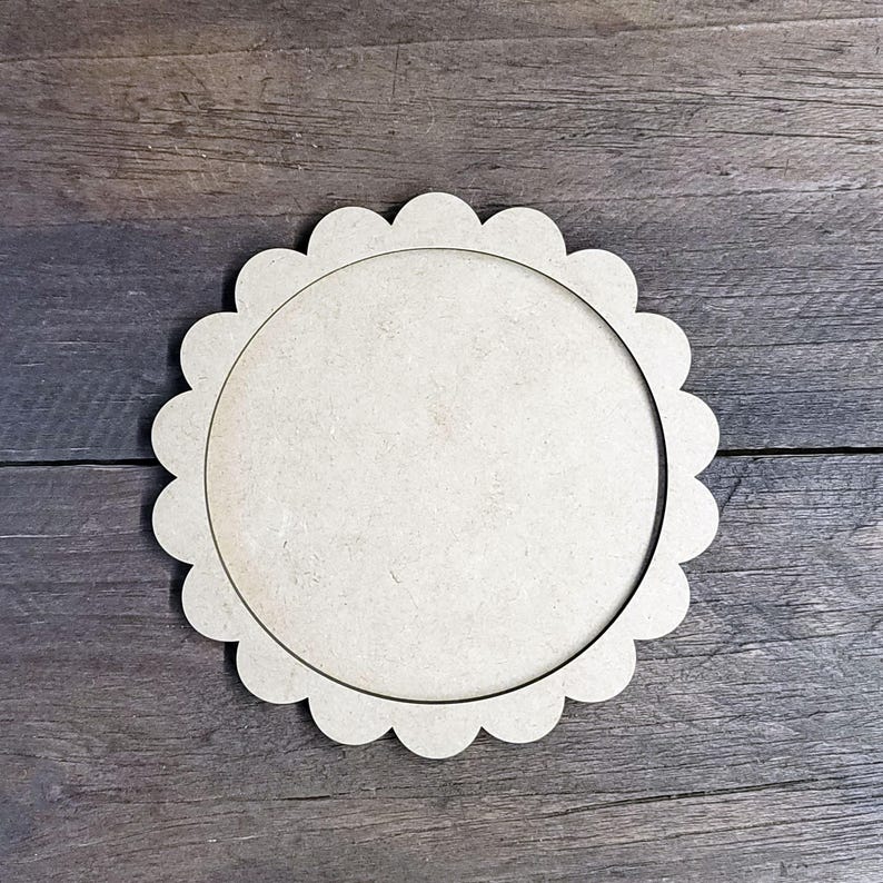May include: A round, unfinished wooden craft blank with a scalloped edge. The blank has a circular interior and is made of light-colored wood, perfect for painting or other DIY projects.