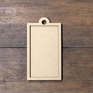 May include: A blank wooden tag with a hole at the top. The tag is rectangular and has a light brown color.