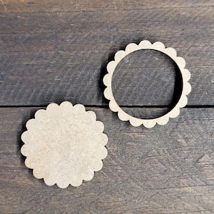 May include: Two unfinished, scalloped-edge wooden circles. One is a solid circle, and the other is a ring. The wood has a light brown color and a natural grain. These craft supplies are ideal for DIY projects and home decor.