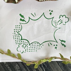 Puede incluir: Estampado verde y blanco con un diseño de globo de diálogo de cómic. El globo de diálogo está vacío y rodeado de rayos verdes y puntos.
