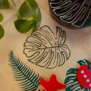 May include: A close-up of a light brown surface with various green leaf designs and a yellow starfish with red dots. There is also a red and blue boat with white dots and a red starfish.