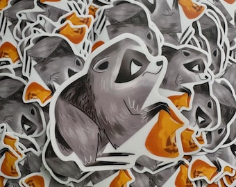 May include: A die-cut sticker featuring a stylized gray raccoon with black eye markings holding a bright orange jack-o'-lantern pumpkin. The raccoon has a pointed snout and is depicted in a side profile view with a mischievous expression.