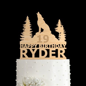 Könnte beinhalten: Holz-Kuchentopper mit einem Wolf, der zum Mond heult, zwei Kiefern und dem Text "Happy Birthday Ryder" mit der Nummer 19.