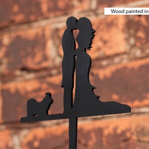 Puede incluir: Silueta de madera negra de una pareja bes&aacute;ndose con un perro peque&ntilde;o delante de ellos. La madera est&aacute; pintada de negro.