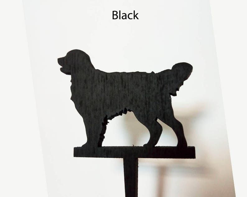 Puede incluir: Silueta de perro de madera negra, de pie sobre una estaca de madera. El perro est&aacute; mirando hacia el lado derecho de la imagen.