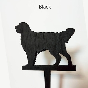 May include: Black wooden silhouette of a dog, standing on a wooden stake. The dog is facing the right side of the image.