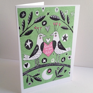 Carte Saint-Valentin - A5 - L’amour est dans l’air - deux oiseaux qui vont juste s’embrasser, carte illustrée verte et rose très romantique.