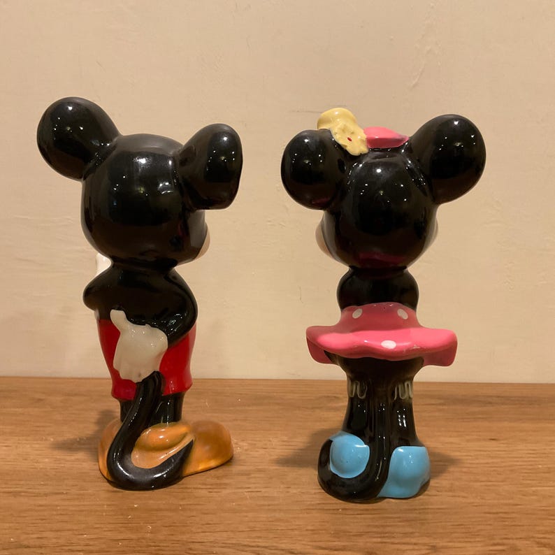 Op de afbeelding: Een paar keramische Mickey Mouse en Minnie Mouse beeldjes. Mickey draagt een rode broek en zwarte schoenen. Minnie draagt een roze stippenjurk en blauwe schoenen.
