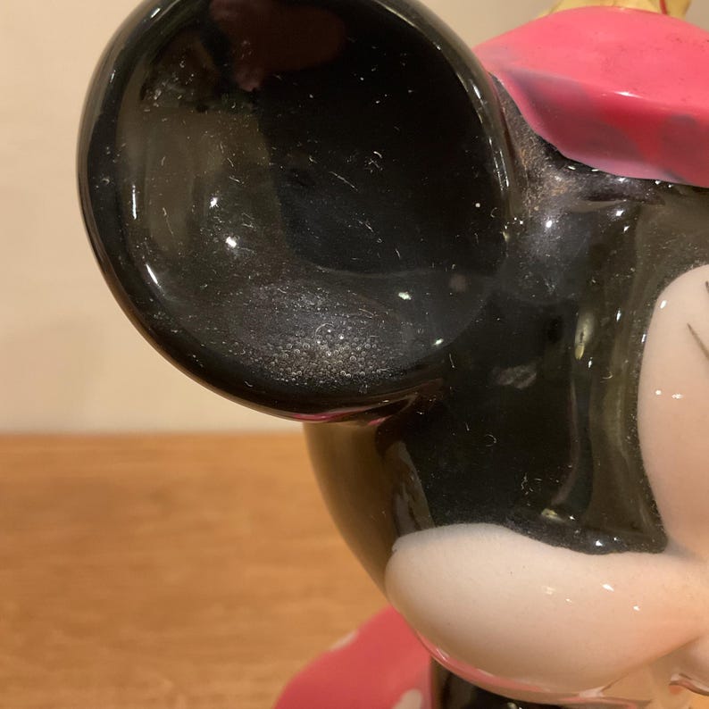 Op de afbeelding: Een zwart-witte keramische figuur van Mickey Mouse met een roze hoed. De figuur zit en heeft een gedetailleerd gezicht.