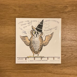 May include: A cartoon owl wearing a black witch's hat with a white brim. The owl is standing on a ruler with the text "INCH = 2.5 CENTIMETERS". The image also includes a list of conversions: "LITER = 1.056 QUARTS", "55 MPH = 88 KM", "70°F = -21°C", "1 OZ = 28 GRAMS", "METER = 1.093 YDS", "KILOMETER = 0.621 MI."