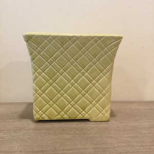 May include: A pale yellow ceramic planter with a square shape and a diamond pattern.