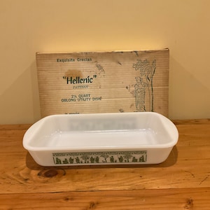 May include: A white 2 1/2 quart oblong utility dish with a green and white "Hellenic" pattern. The dish is sitting on a wooden surface. The box for the dish is visible in the background.
