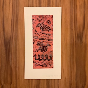 May include: A red and black linocut print on white paper. The print features stylized bird and turtle figures, along with other geometric shapes. The background has a textured pattern. The print is mounted on a white paper.