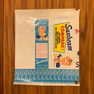 May include: Vintage Sunbeam bread bag with a blue and white design. The bag features the Sunbeam logo, illustrations of a child, and text that reads "Compare! No holes, no streaks, no poor end slices."