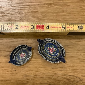 May include: A set of three blue and gold nesting bowls with a hand-painted floral design. The bowls are decorated with red, white, and yellow flowers.
