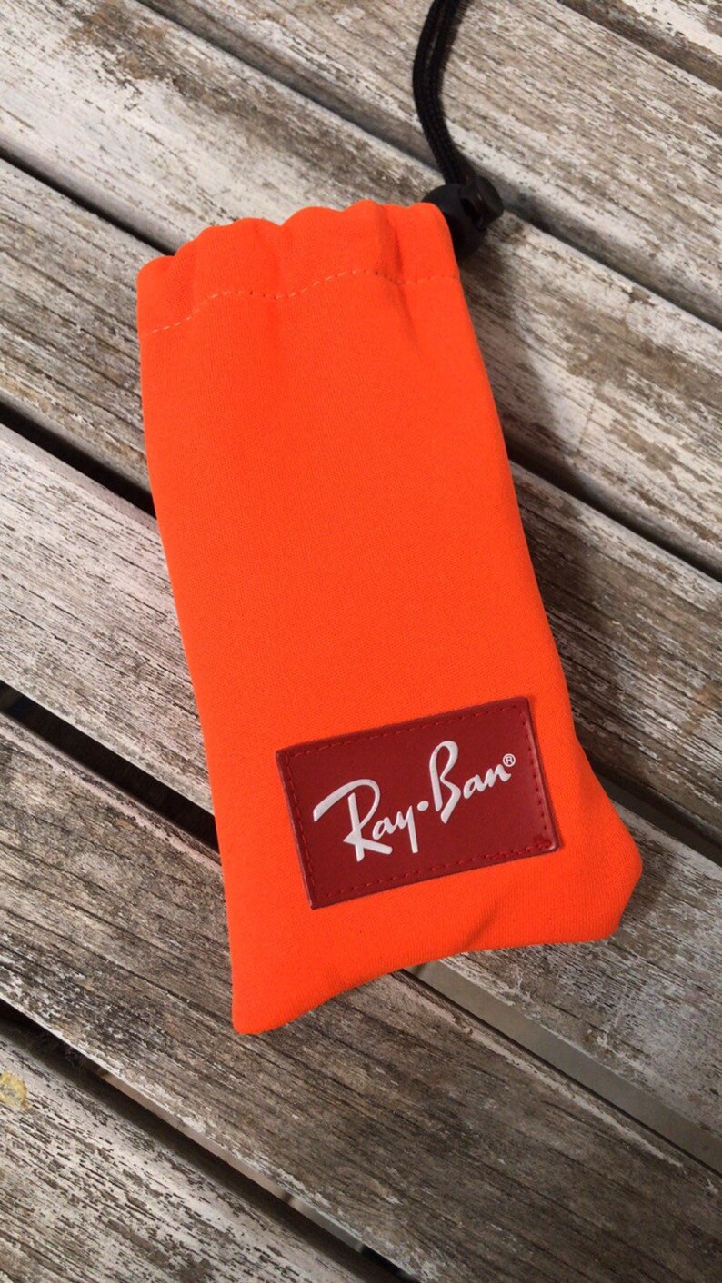 May include: Orange sunglasses case with a red Ray-Ban logo.