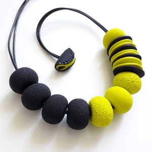 May include: A black and yellow necklace with large round beads. The necklace has a simple clasp closure.