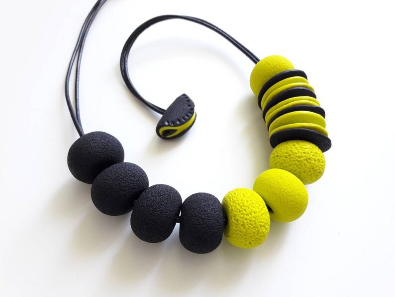 May include: A black and yellow necklace with large round beads. The necklace has a simple clasp closure.