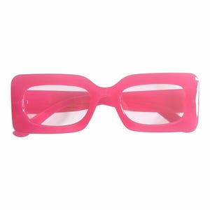 Może przedstawiać: Para okularów w jaskraworóżowej, prostokątnej oprawie. Okulary mają grubą, solidną oprawę i przezroczyste soczewki. Ogólny design to odważny, nowoczesny styl, odpowiedni do mody lub kostiumów.