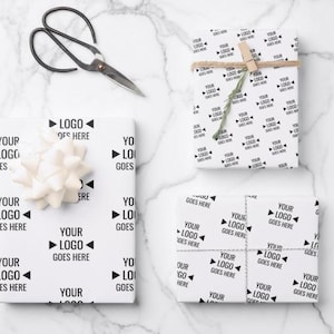 May include: White gift wrap with a repeating pattern of "YOUR LOGO GOES HERE" in black. The image includes wrapped gifts, a pair of scissors, a white bow, and twine.
