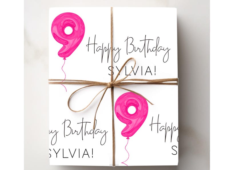 Może przedstawiać: Zapakowany prezent z białym tłem, zawiązany sznurkiem. Prezent jest ozdobiony r&oacute;żowymi balonami z numerem dziewięć i napisem "Happy Birthday SYLVIA!" czarnym pismem.