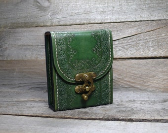 May include: A small, green leather pouch with a brass clasp. The pouch has an intricate, embossed design.