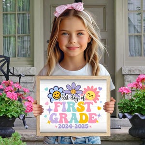 K&ouml;nnte beinhalten: Ein M&auml;dchen h&auml;lt ein Schild mit der Aufschrift "Letzter Tag der ersten Klasse 2024-2025". Das Schild ist mit bunten Blumen und Smiley-Gesichtern verziert und befindet sich in einem Holzrahmen.