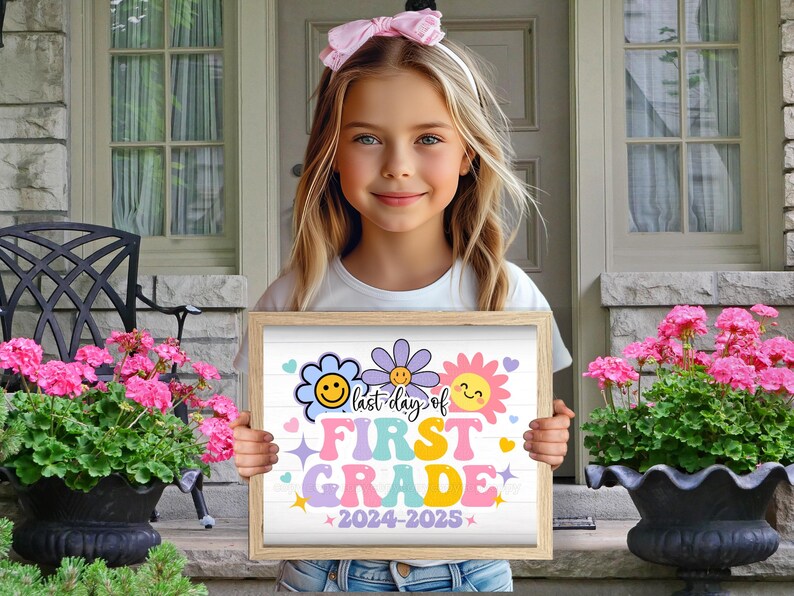 K&ouml;nnte beinhalten: Ein M&auml;dchen h&auml;lt ein Schild mit der Aufschrift "Letzter Tag der ersten Klasse 2024-2025". Das Schild ist mit bunten Blumen und Smiley-Gesichtern verziert und befindet sich in einem Holzrahmen.