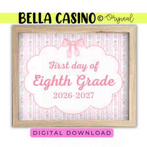 May include: A rectangular wooden frame containing a sign with a pink and white striped background featuring small floral patterns. A pink bow sits above a white scalloped label with the text First day of Eighth Grade and the years 2026-2027.