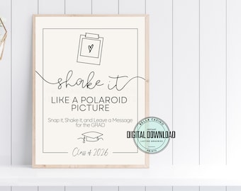 May include: A framed print with the text "shake it like a Polaroid picture." The black text is on an off-white background, with a Polaroid camera graphic. The bottom of the print reads "Class of 2026."