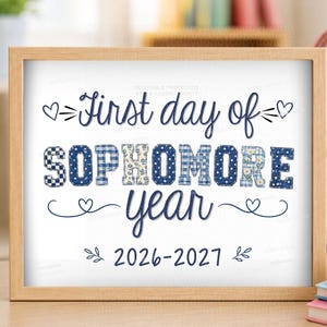 May include: A rectangular wooden frame containing a white sign with the dark blue text First day of SOPHOMORE year 2026-2027. The word SOPHOMORE features a blue and white patchwork pattern with various floral, gingham, and polka dot designs.