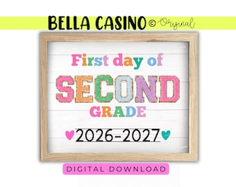 May include: A framed sign with a white wood-plank background featuring the text First day of SECOND GRADE in colorful glitter-style varsity letters. Below, the text 2026-2027 is written in black with a pink heart on the left and a teal heart on the right.