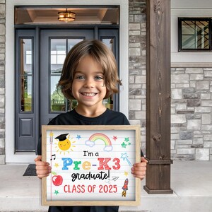 K&ouml;nnte beinhalten: Ein Kind h&auml;lt ein Schild mit der Aufschrift "Ich bin ein Pre-K3 Absolvent! Klasse von 2025". Das Schild ist mit einem Regenbogen, Sternen, einer Rakete und einer M&uuml;tze verziert.